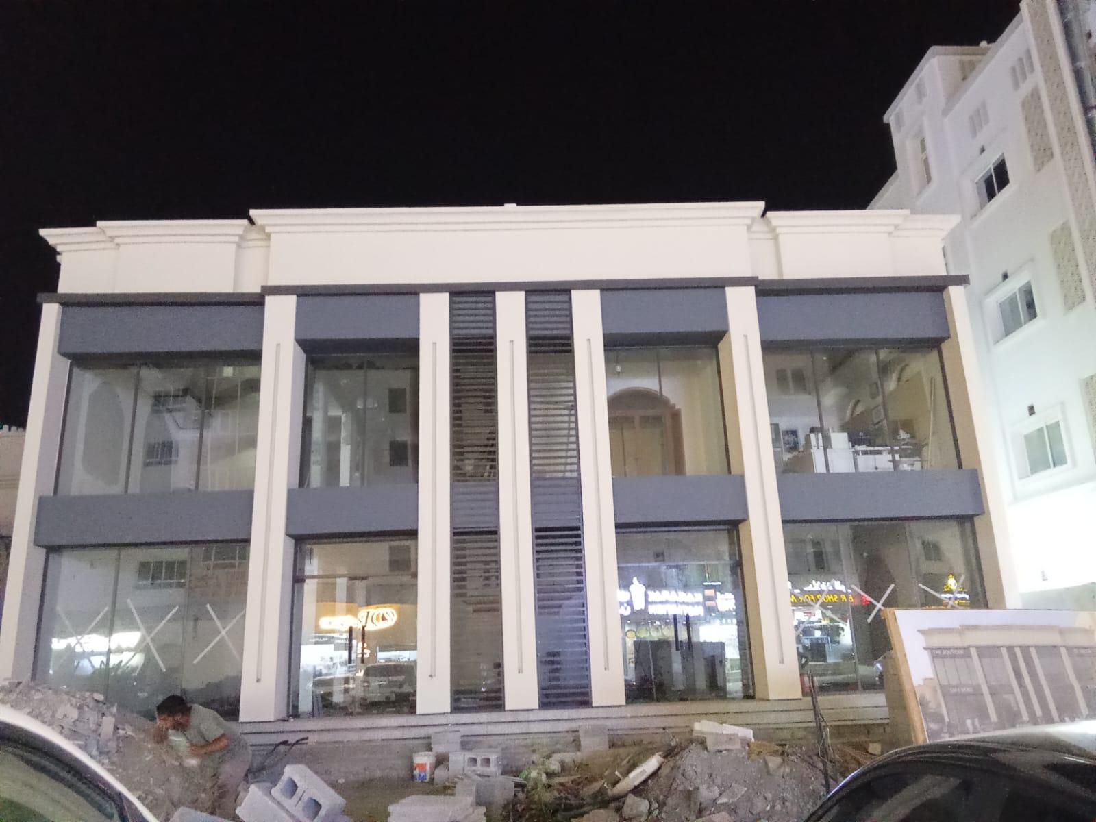 Two-storey commercial glass façade at night in Oman