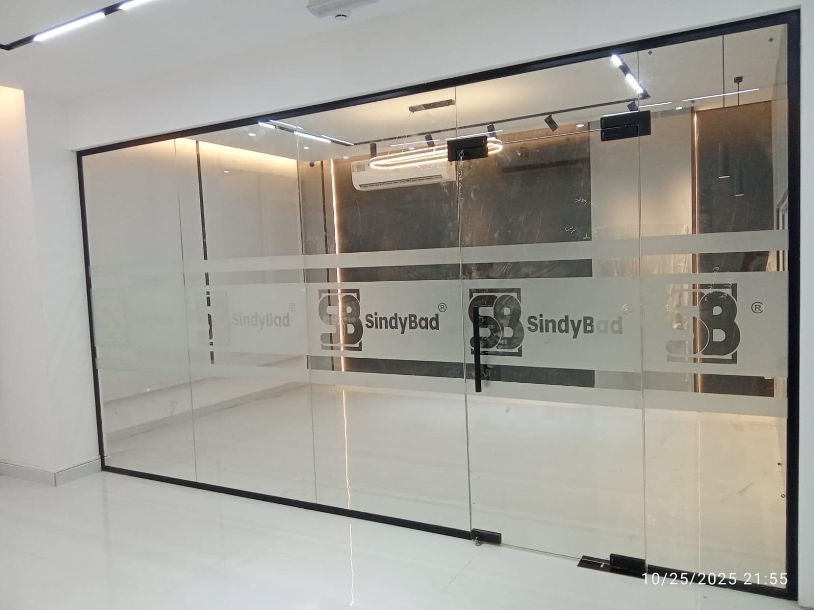 Black-frame office glass wall with frosted branding band, installed by Oman Glass House in Muscat