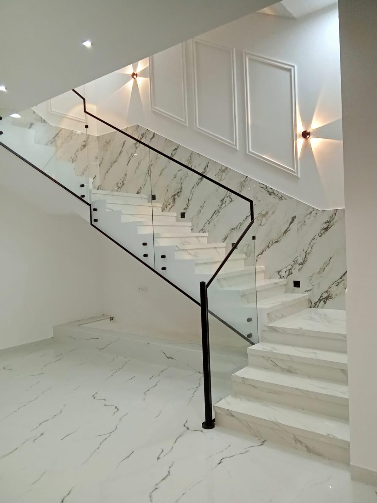 Side-mounted frameless glass stair panels on veined marble in an Oman villa