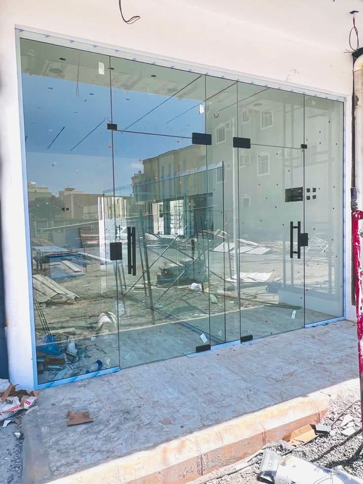 Frameless glass shopfront with black pull handles