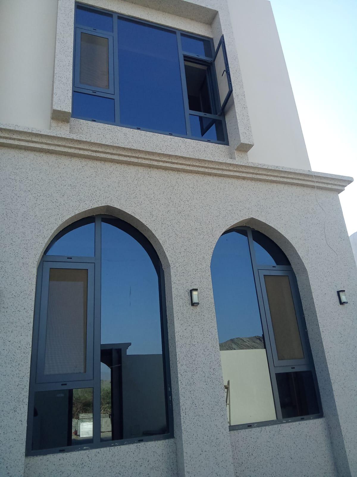 Dark aluminium arched windows with blue heat-reducing glass on a villa façade
