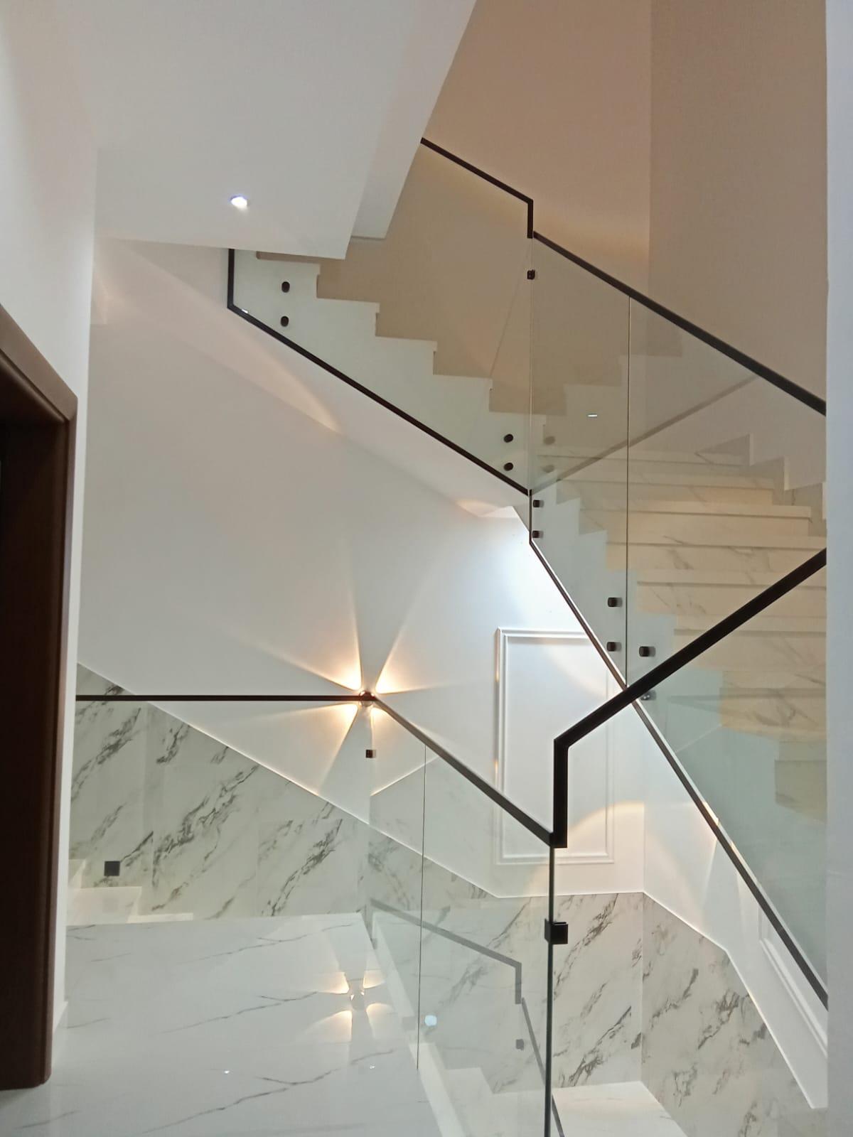 Frameless tempered glass stair balustrade with slim black handrail